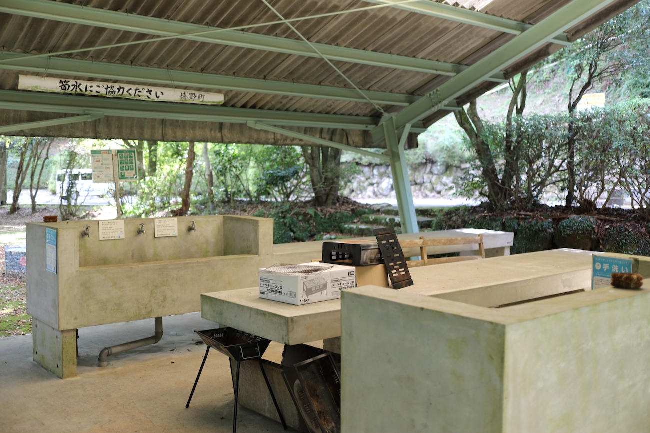 Covered outdoor cooking area with concrete sinks and worktables at the campground.