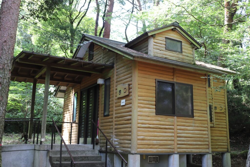 Wooden cabin named “Matsu” surrounded by tall forest trees.