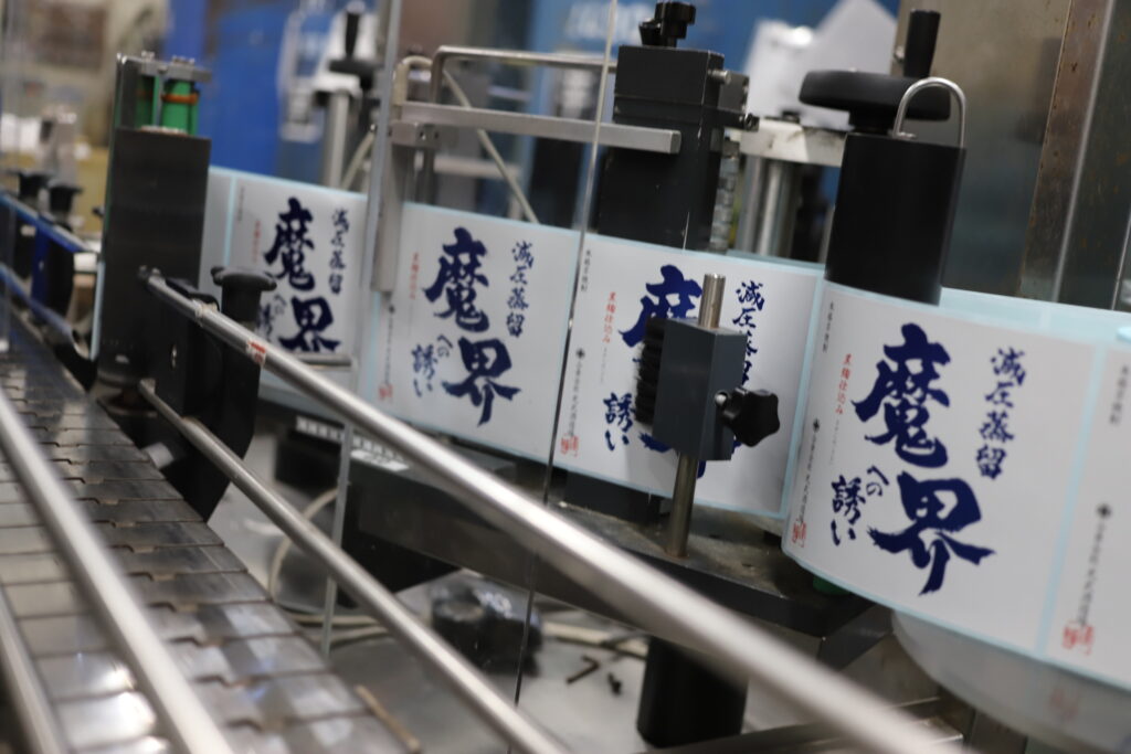 Bottling line with labels of “Makai e no Izanai,” a shochu brand produced by Mitsutake Brewery in Kashima, Saga.