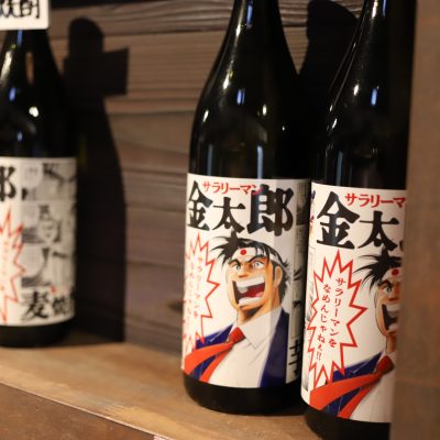 Mitsutake × Salaryman Kintaro Collaboration Shochu Bottles of Mitsutake shochu featuring collaboration labels with the manga series Salaryman Kintaro, displayed at Mitsutake Brewery in Kashima, Saga.